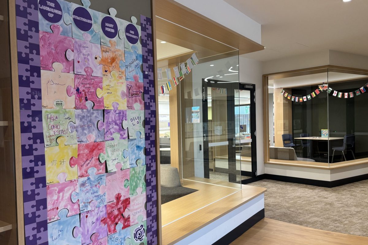 Hand cut puzzle pieces fitting showing greetings and blessings written and coloured by students with different flags hanging in the background